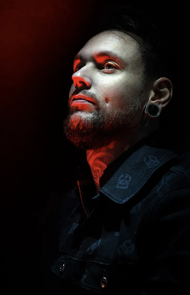Portrait of tattoo artist Sandry Riffard illuminated by red light
